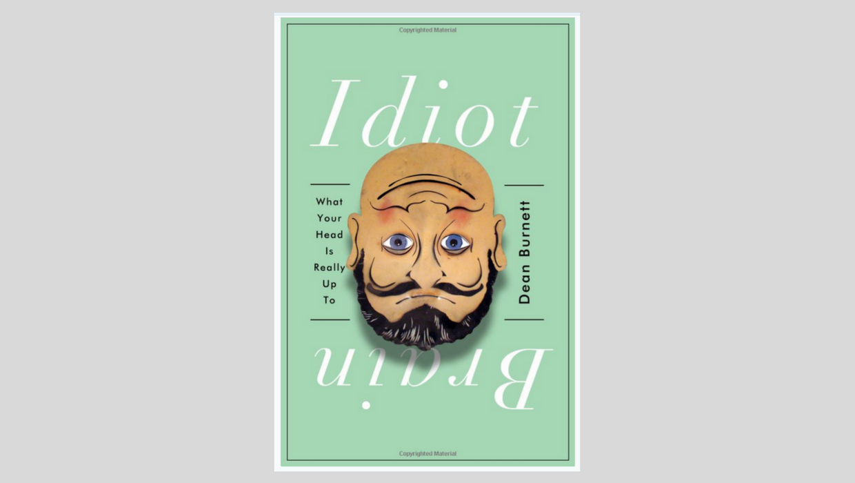 (Descrição da imagem: Capa do livro Idiot Brain. A capa mostra uma imagem de ilusão de ótica onde o desenho do rosto de um homem parece estar tanto de cabeça para cima como de cabeça para baixo)